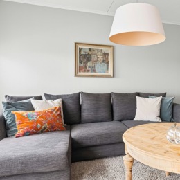a living room with a couch table light and art on the wall