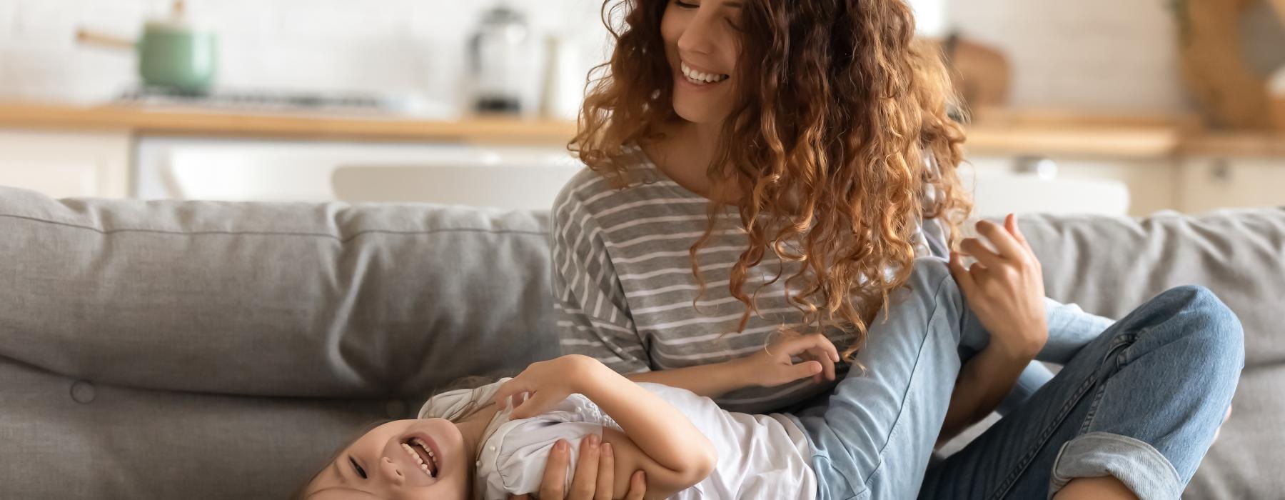 a woman and child playing on a couch