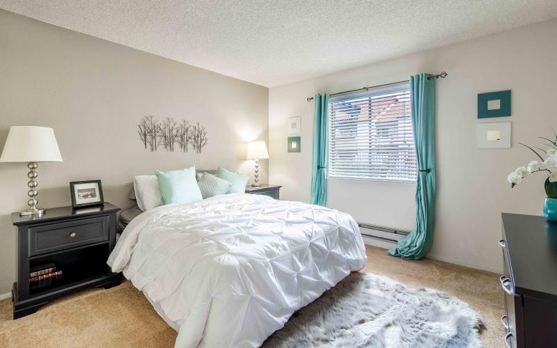 a bedroom with a bed tables lamps and a window